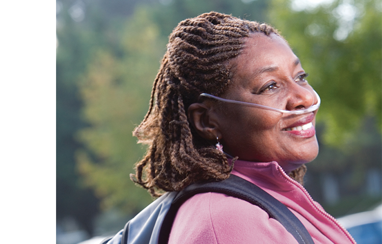 Person with nasal cannula walking outdoors.