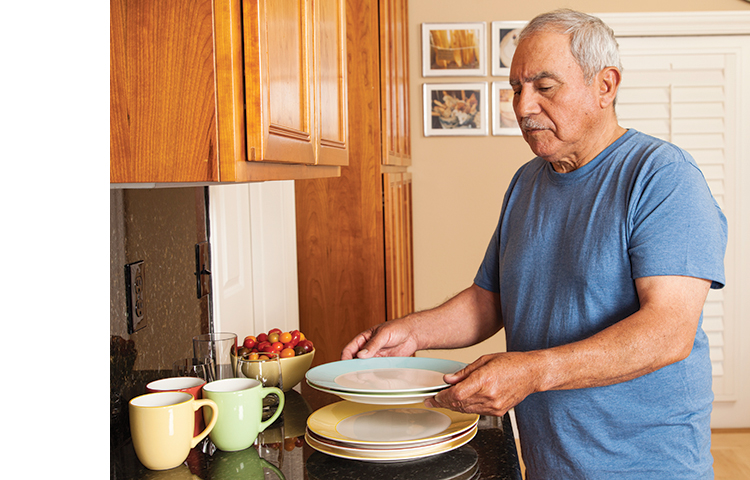 Person stacking plates on the counter to limit the need to reach into the cabinet for them.