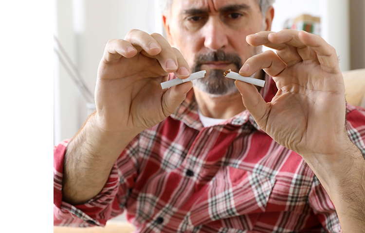 Person breaking a cigarette in half.