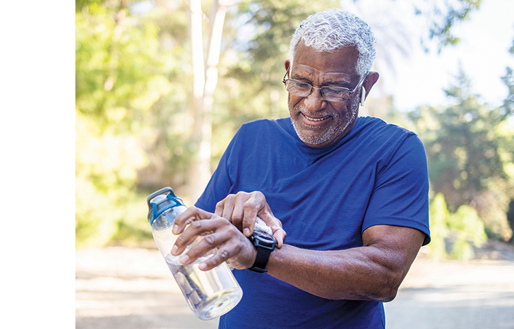 Person outside exercising while setting their watch and holding a water bottle.