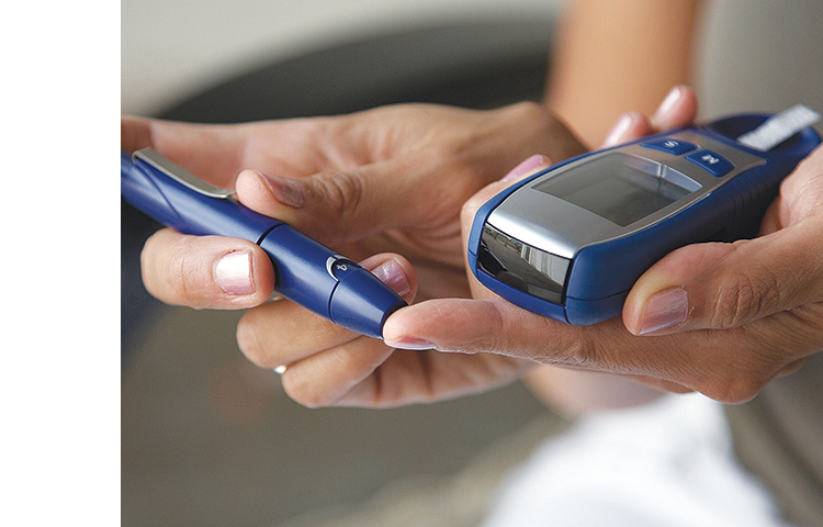 Close-up of hands using a lancet on their finger to test their blood sugar.