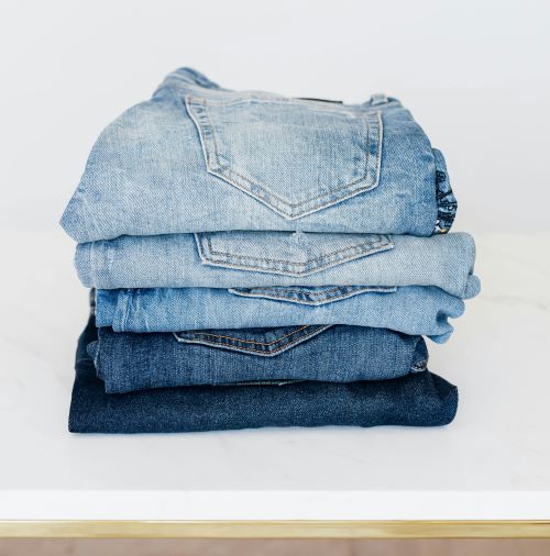 Stack of jeans on white shelf