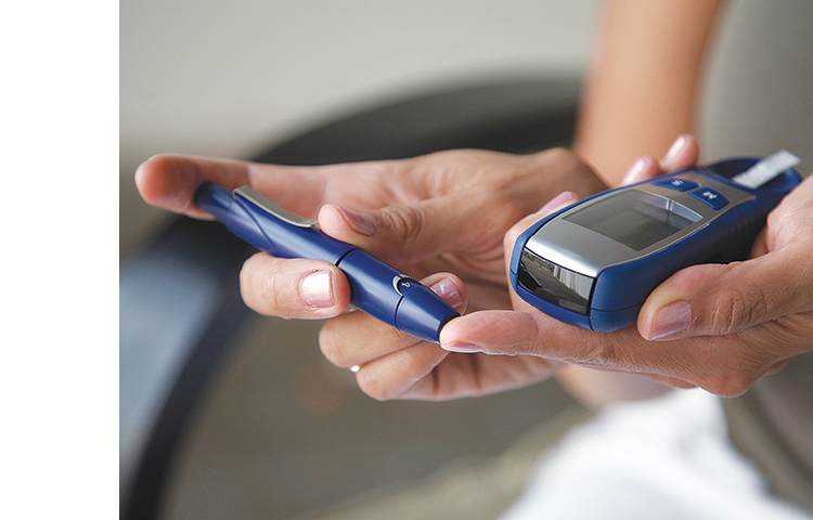 Closeup of hands using blood sugar test kit.