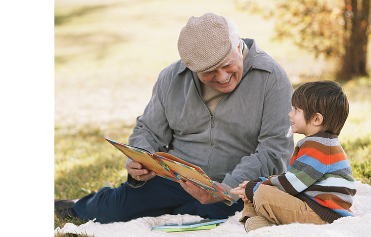 Person reading to a child outside.