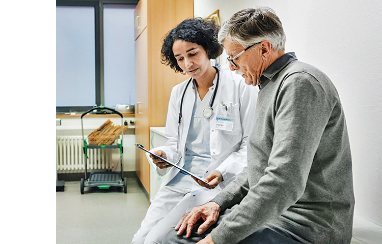 Healthcare provider reading off a clipboard to a person sitting next to them.