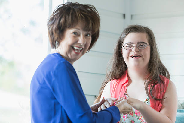 Image description: An older caregiver is seen assisting a young adult with Down's Syndrome, showcasing care and guidance.