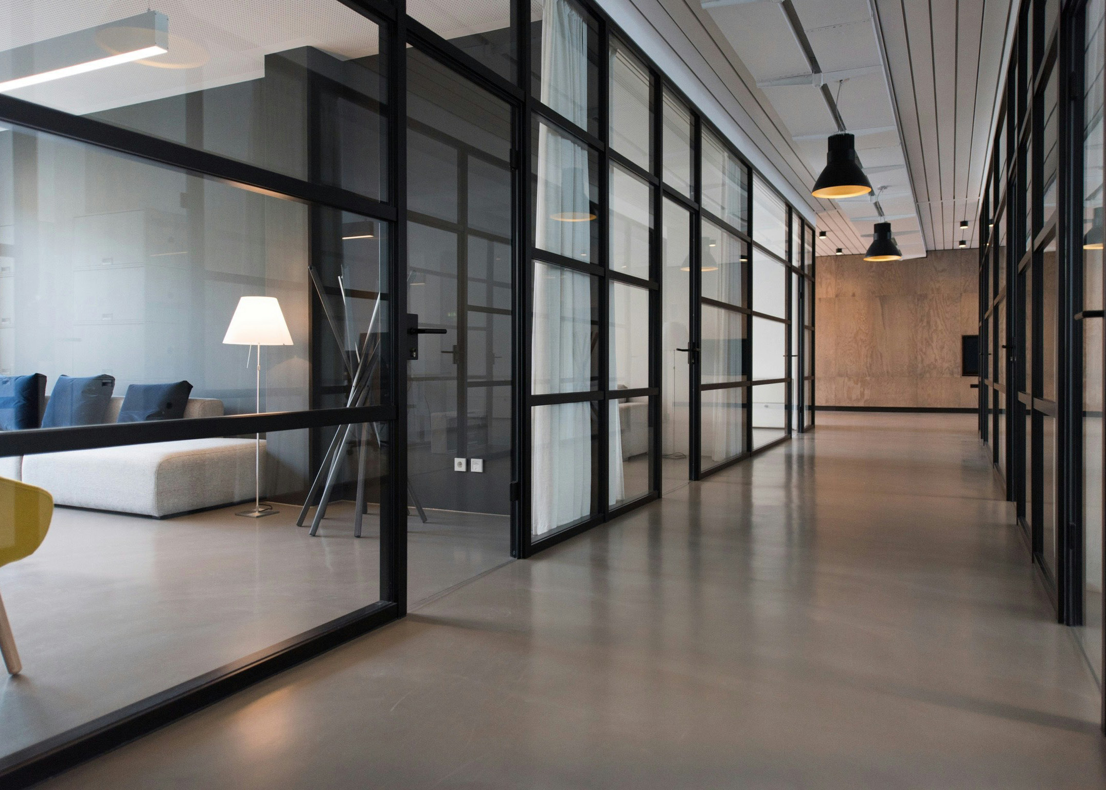 An interior office hallway with large glass walls.
