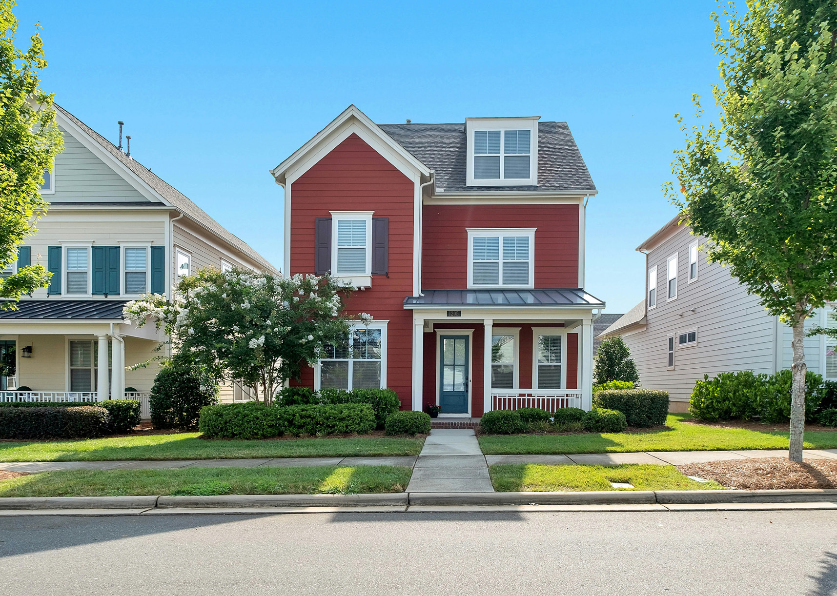 A red, single-family house on a suburban street.