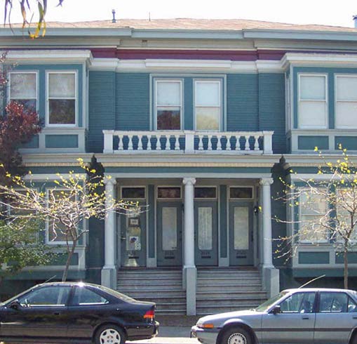 A wide, light blue building with many windows and two doorways.